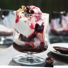 an ice cream sundae with cherries and whipped cream in a glass on a table