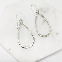 "These contemporary earrings consist of Sterling silver wire formed by hand into teardrops, and hammered to reflect the light beautifully. They are attached to a wire ear hook, which shows them off and ensures a lightweight dangle for every day wear.  - 50mm drop - quality ear-hook - hypoallergenic  - 925 Sterling Silver  - Hand Made Item The perfect pair to finish off your every day street style or minimalist wardrobe.  As you aware that each earring is forged by hand, therefore ever so slightly different from one another to give it an uniqueness about it.  Your earrings comes with a \".925\" sterling silver stamp as a symbol of guaranteed product quality as well as beautifully packaged in a branded box, ready for gifting, or spoiling yourself with a personalized piece. Free polishing clo Hammered Teardrop Metal Earrings, Hammered Metal Teardrop Earrings, Minimalist Hammered Drop Earrings, Hammered Teardrop Earrings, Silver Hammered Teardrop Dangle Earrings, Hammered Teardrop Sterling Silver Hoop Earrings, Hammered Sterling Silver Teardrop Hoop Earrings, Modern Teardrop Hand Forged Hoop Earrings, Everyday Hand Forged Teardrop Earrings