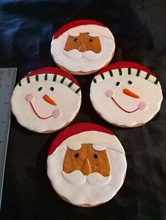 four decorated cookies sitting on top of a black cloth covered table next to a ruler