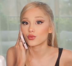 a woman holding a cell phone to her ear and looking at the camera with an intense look on her face