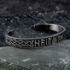 a silver bracelet with the word faith on it sitting on top of a stone slab