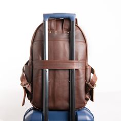 a brown backpack sitting on top of a blue suitcase