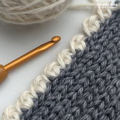 the crochet is next to yarn and a knitting needle