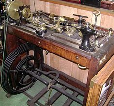 an old fashioned sewing machine on wheels in a room with wood paneling and other items