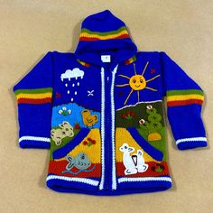 a child's blue jacket with animals and clouds on the front, sitting on a beige surface