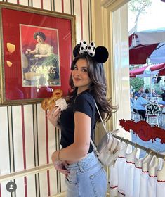 a woman holding a donut in front of a painting on the side of a wall