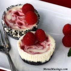 two cupcakes with raspberries on top are sitting on a plate