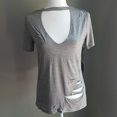 a white mannequin wearing a gray shirt with holes on the front and back