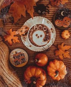 a cup of coffee with a smiley face drawn in it surrounded by pumpkins and other decorations