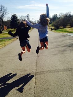 two people jumping in the air on a street