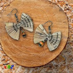 two fan shaped earrings sitting on top of a piece of wood