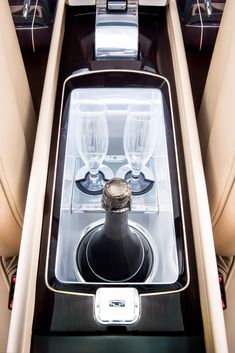 the interior of a car with two empty wine glasses and a bottle in the center