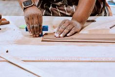 a person is working on some wood with their hands and tools in front of them