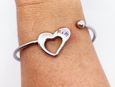 "This minimalist heart cutout charm bangle bracelet is a perfect gift for a bride, a romantic gift for Valentines Day or even with kids names for Mother's Day. - I'll engrave couple's initials on the heart of the stainless steel bangle. -Add small 5/8\" charms with a wedding date (& small heart) or a baby name/birthdate (I can engrave small baby feet instead of a heart if you'd like). (Main sample picture shows one disc charm with a wedding date and small heart.)" Personalized Stackable Rings, Bracelet For Bride, Gift For Valentines Day, Personalized Bracelet, Kids Names, Stainless Steel Bangles, Bangle Bracelets With Charms, Small Baby, Personalized Bracelets