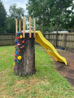 a tree stump with toys on it and a slide in the back yard behind it