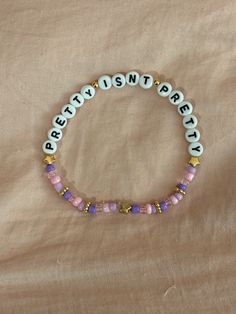 A hand-crafted glass bead friendship bracelet highlighting Olivia Rodrigo's song "Pretty Isn't Pretty"! A simple and cute way to show off your favorite song or a great concert accessory!  This bracelet is made with Czech glass beads, plastic letter beads, plastic spacer beads, and is on an elastic thread measured at about 10 inches in length for a relaxed/loose fit. If you would like the bracelet you order to be smaller or larger, please leave the requested size in inches in the personalization Adjustable Beaded Kpop Bracelets, Adjustable Round Beads Kpop Bracelets, Trendy Beaded Name Bracelet For Friendship, Adjustable Kpop Style Friendship Bracelets With Letter Beads, Trendy Purple Beaded Bracelets For Festival, Olivia Rodrigo Friendship Bracelet Ideas, Olivia Rodrigo Friendship Bracelet, Olivia Rodrigo Bracelets, Olivia Rodrigo Bracelet Ideas