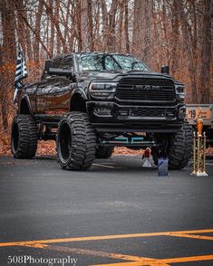 a large black truck parked on the side of a road in front of some trees