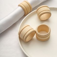 three wooden rings sitting on top of a white plate next to a toothbrush holder