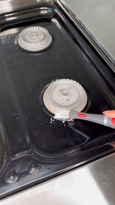 someone is cleaning the burners on an electric stove with a red toothbrush in their hand