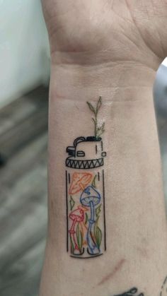 a person with a tattoo on their wrist holding up a small jar filled with flowers