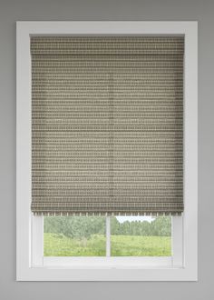 a window with a roman blind in front of it and a green field behind it