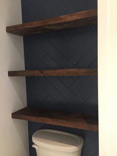 a white toilet sitting next to two wooden shelves