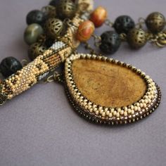 a beaded necklace with beads and a pendant on it's end, sitting next to other beads