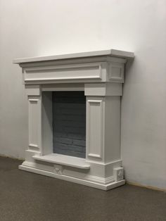 an empty fireplace in a room with white walls