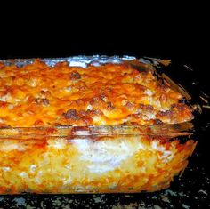 a casserole dish sitting on top of a stove covered in cheese and meat