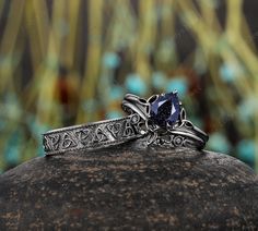 two silver rings with a blue stone in the middle on top of a rock next to some flowers