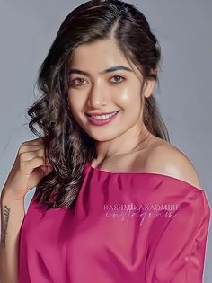 an image of a woman posing for the camera with her arm around her shoulder and wearing a pink top