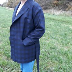 a woman standing on top of a grass covered field next to a green field with trees