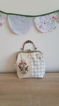 a purse sitting on top of a wooden table next to a bunting banner with flowers