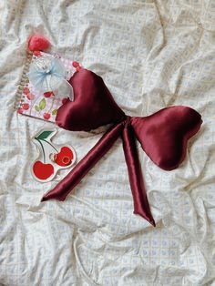 the bow is laying on the bed next to an apple and cherry sticker book