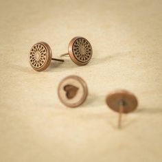 two pairs of earrings sitting on top of a table next to a pair of screws