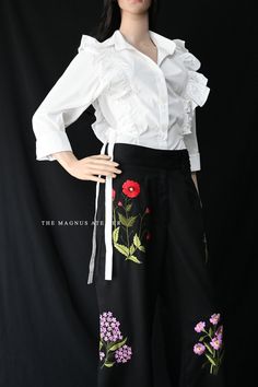 Step into timeless elegance with these luxurious black wide-leg pants, beautifully adorned with intricate floral embroidery in vibrant hues. The carefully designed blooms, featuring red poppies, lilac, and delicate green leaves, add a touch of femininity and sophistication. Perfect for any occasion, these pants offer a unique blend of style and comfort with their flowing silhouette. As a special offer, enjoy a free pure cotton poplin shirt with delicate ruffled detailing. This classic white shir Spring Embroidered Wide-leg Pants, Embroidered Wide Leg Trousers For Spring, Floral Embroidered Trousers For Spring, Spring Black Embroidered Pants, Elegant Summer Pants With Floral Embroidery, Spring Embroidered Black Pants, Elegant Embroidered Summer Pants, Elegant Cotton Bottoms With Floral Embroidery, Traditional Spring Bottoms With Embroidered Hem