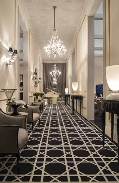 an elegant hallway with chandeliers and black and white flooring is pictured in this image