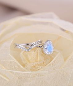 two white gold rings with blue topaz and diamonds on a piece of lace covered fabric