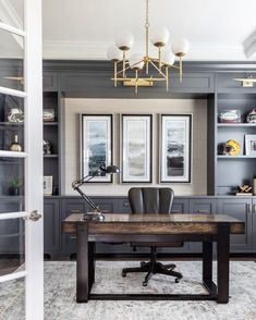 an office with gray cabinets and a wooden desk in front of two framed pictures on the wall