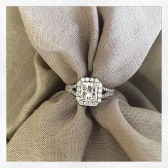 an engagement ring sitting on top of a beige cloth covered chair with a white diamond center stone