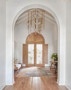 an archway leading into a living room with wooden floors and white walls, along with a chandelier hanging from the ceiling