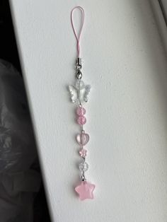 a pink and white key chain hanging from a wall