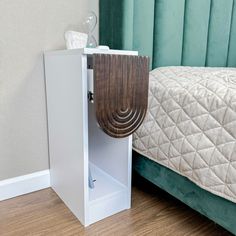 a bed with a green headboard next to a white cabinet and wooden flooring