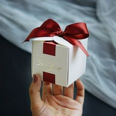 a person holding a white box with a red bow