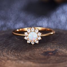 an opal and diamond ring sits on top of a piece of wood