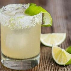 a close up of a drink with lime and sugar on the rim next to sliced limes