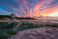 the sun is setting over the beach and sand dunes