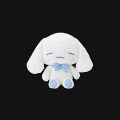 a white stuffed animal with a blue bow on it's neck and eyes closed