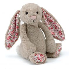 a gray stuffed rabbit with red flowers on it's ears and tail, sitting in front of a white background