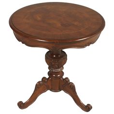 a wooden table with carved legs and a round top on an isolated white background,